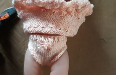 a baby doll is wearing a white knitted bodysuit