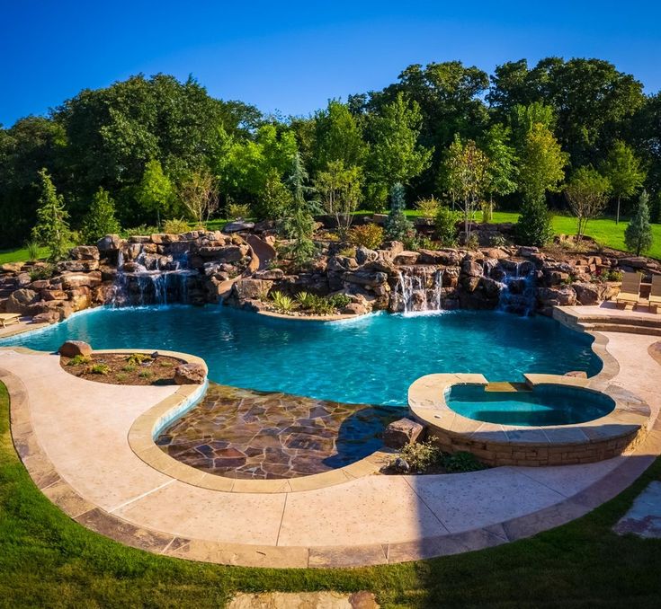 an outdoor swimming pool surrounded by lush green trees and water features, including a waterfall