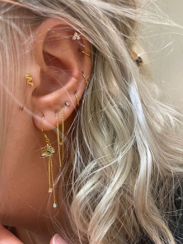 a woman with blonde hair wearing gold ear cuffs and piercings on her left ear