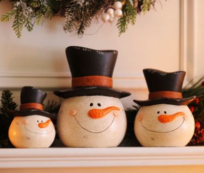 three snowmen sitting on top of a mantle