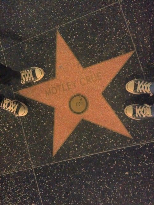 two people standing in front of a star on the hollywood walk of fame with their feet up