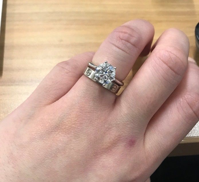 a person's hand with a ring on it and a camera in the background