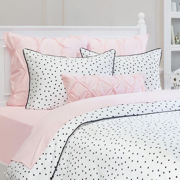 a white and pink bed with polka dots on the comforter, pillows and pillow cases