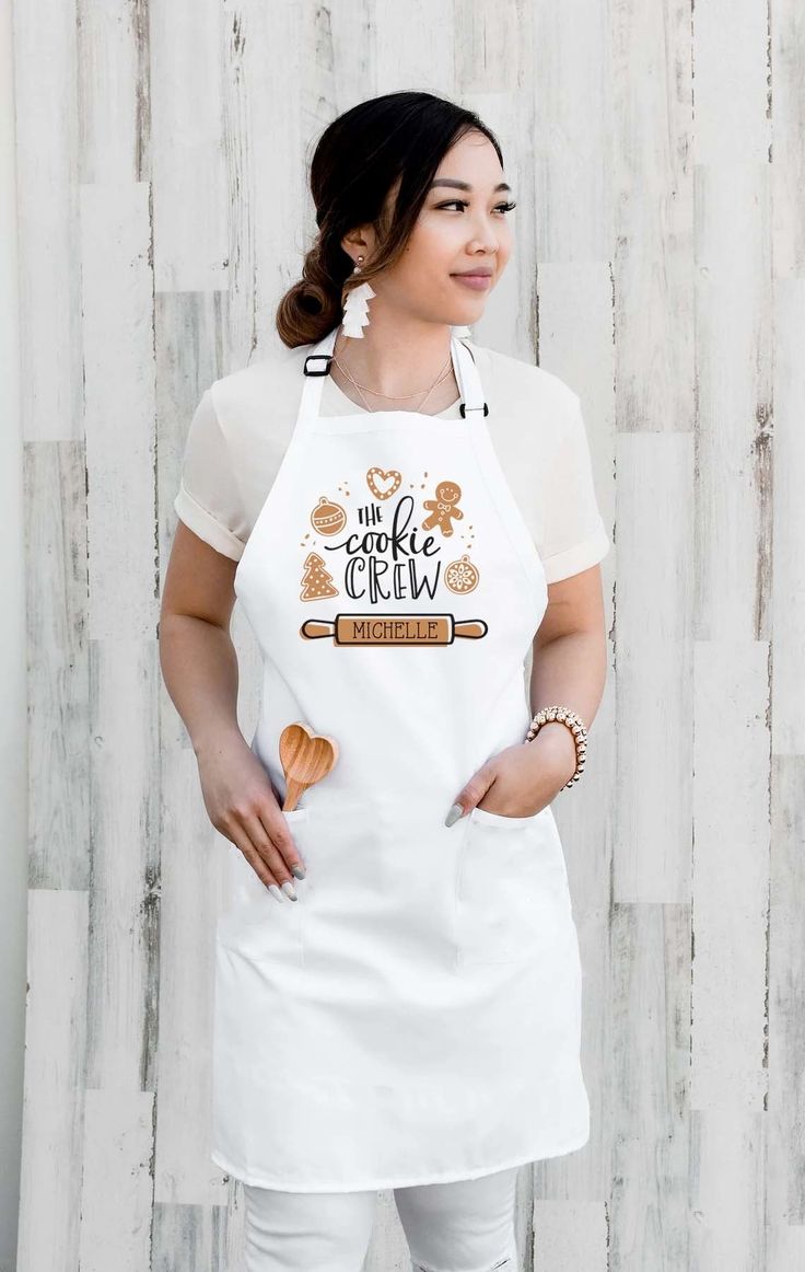 a woman wearing an apron and holding a wooden spoon in front of a white wall