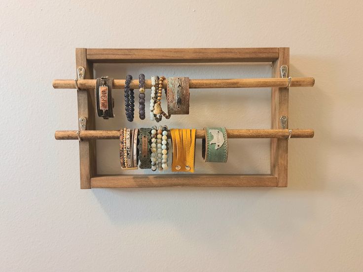 a wooden rack with bracelets hanging from it's sides and on the wall