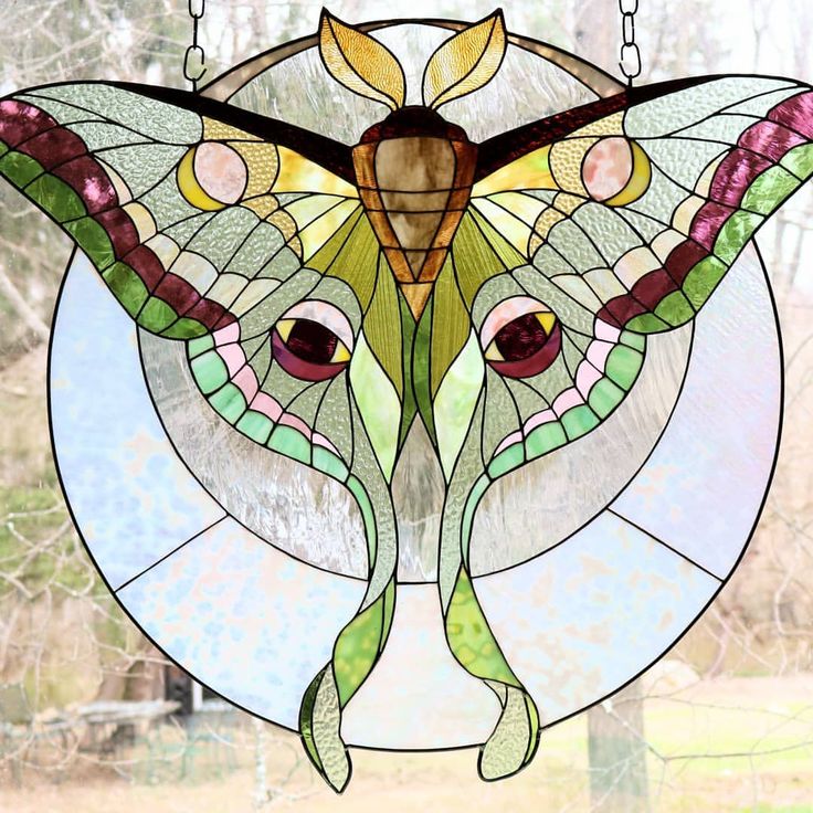 a close up of a stained glass window with a butterfly on it's face