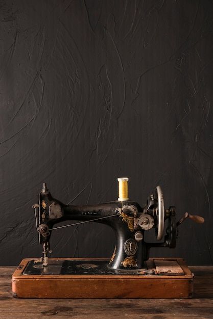 an old sewing machine sitting on top of a wooden table next to a black wall