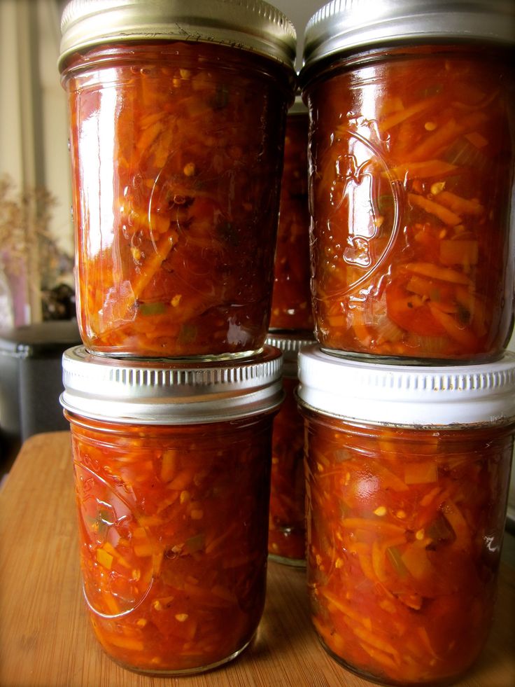 four jars filled with carrots sitting on top of a wooden table