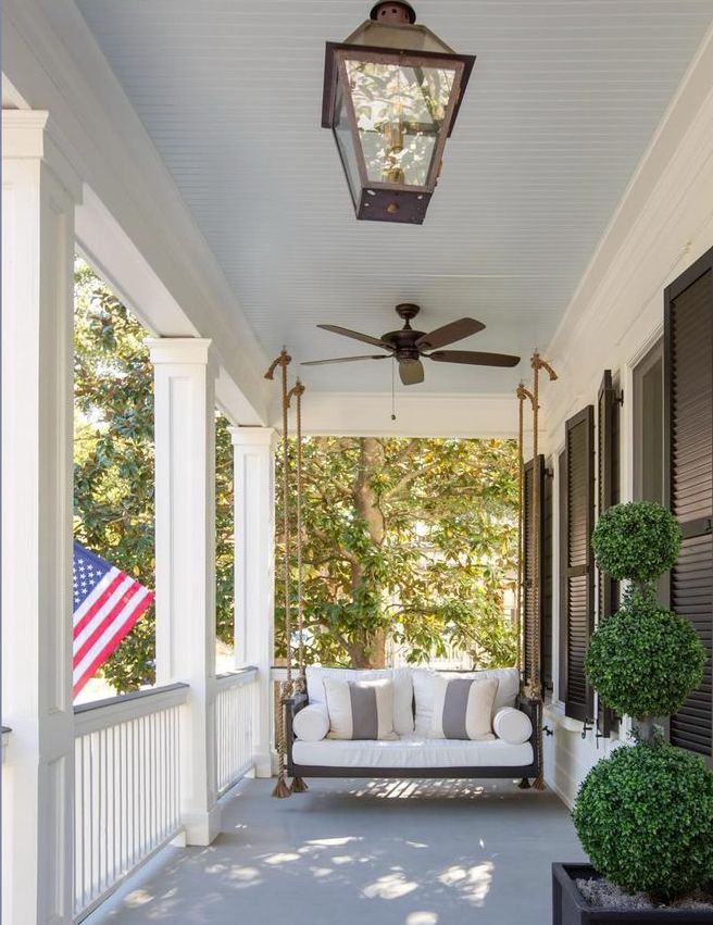 a porch with a white couch and ceiling fan