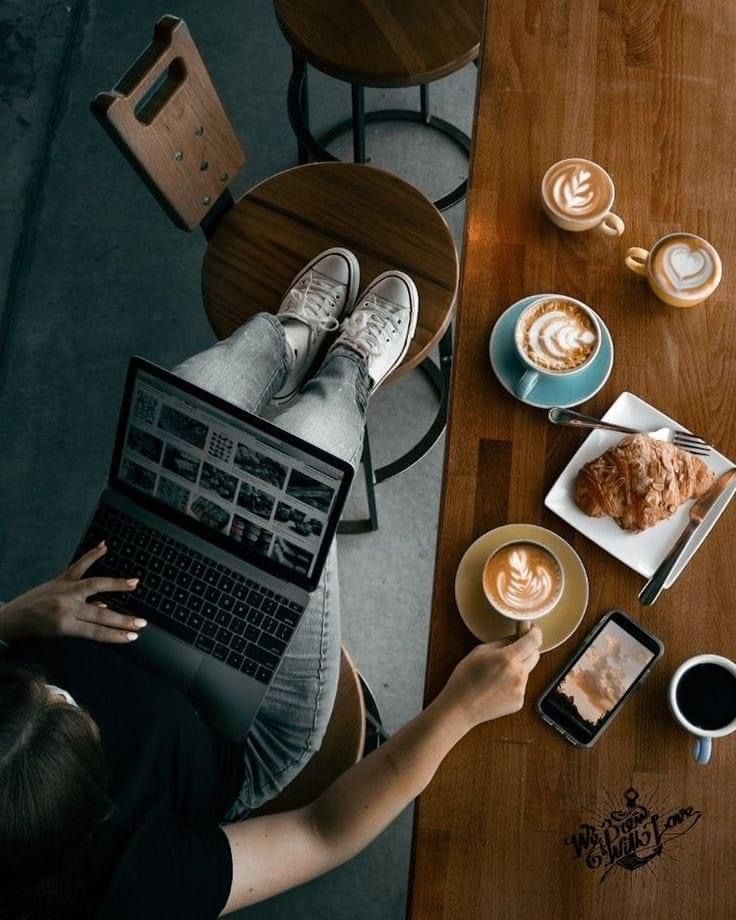 a person is sitting at a table with their laptop and some food on the table