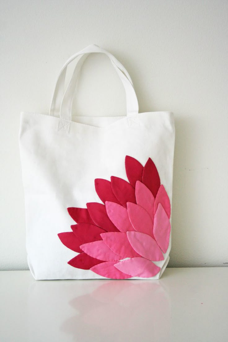 a white bag with pink and red flowers painted on it sitting on a table next to a wall