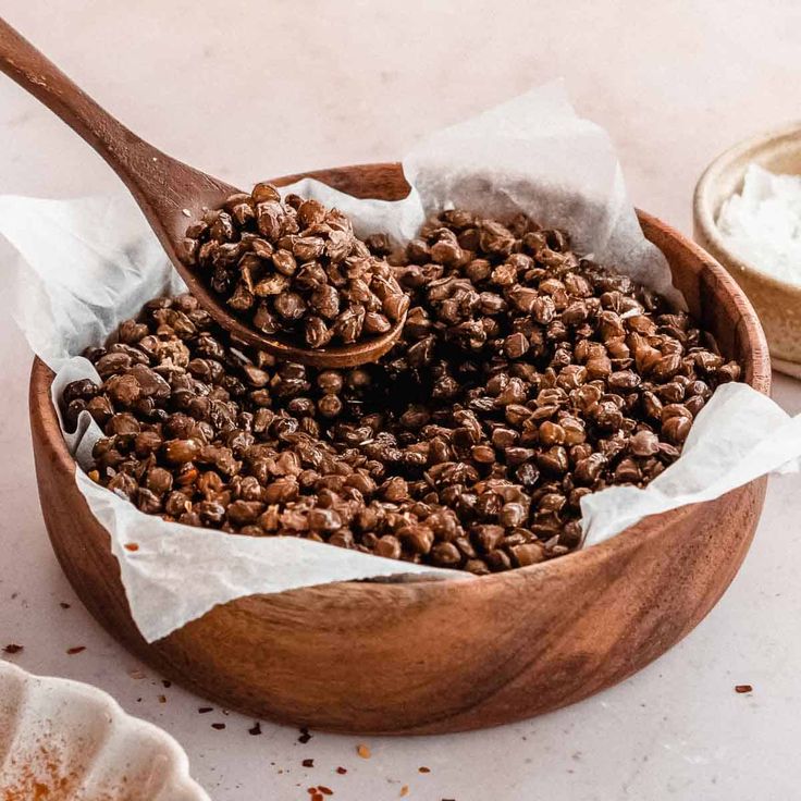 a wooden bowl filled with granola on top of a table next to a spoon