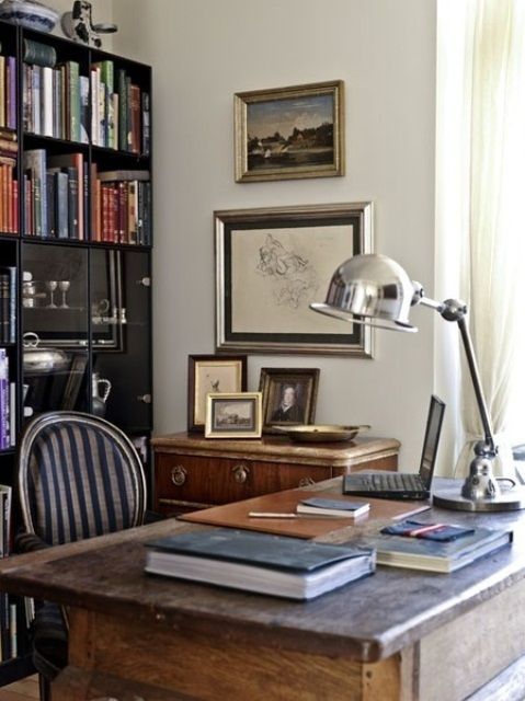 a room with a desk, bookshelf and pictures on the wall