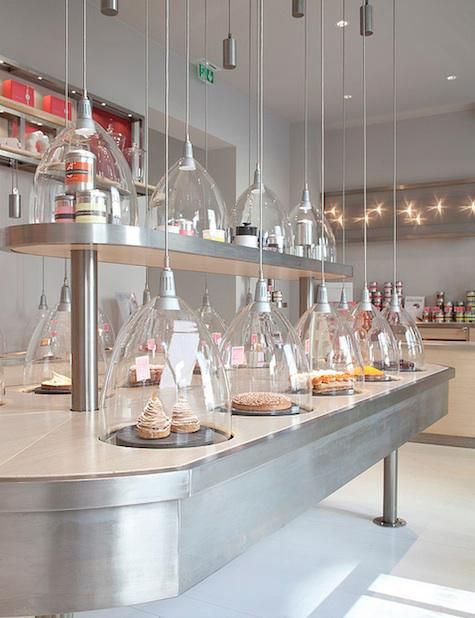 a counter with lots of glass domes hanging from it's sides and food in the middle