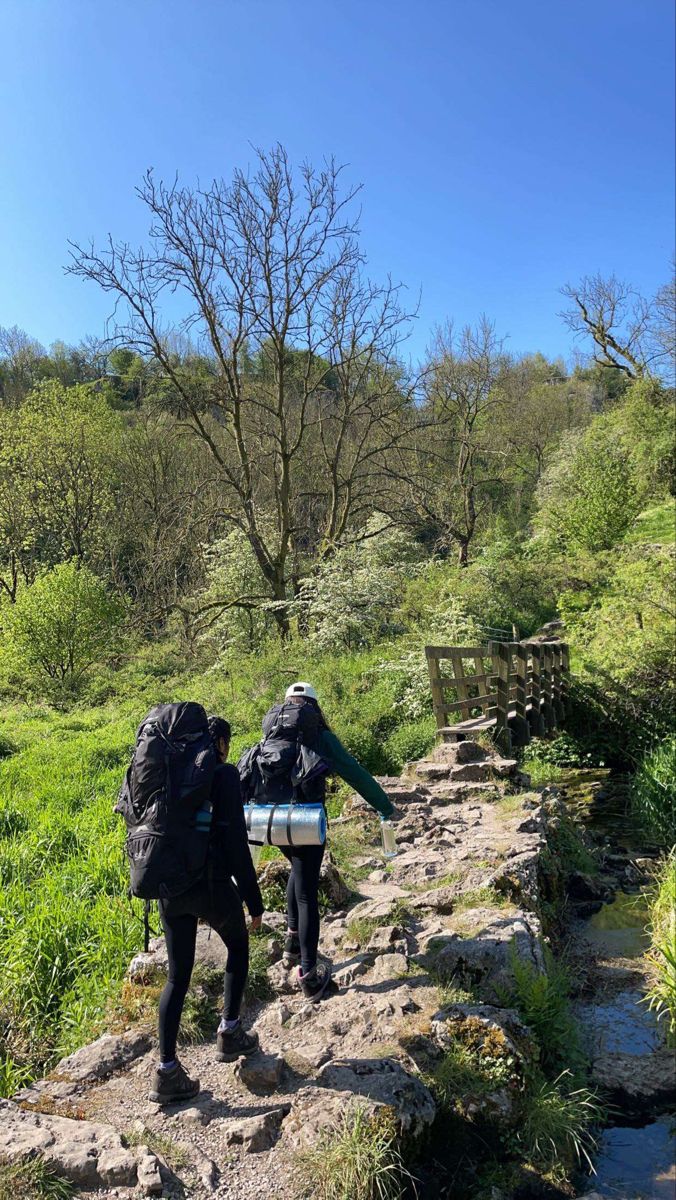 two people with backpacks walking up a trail