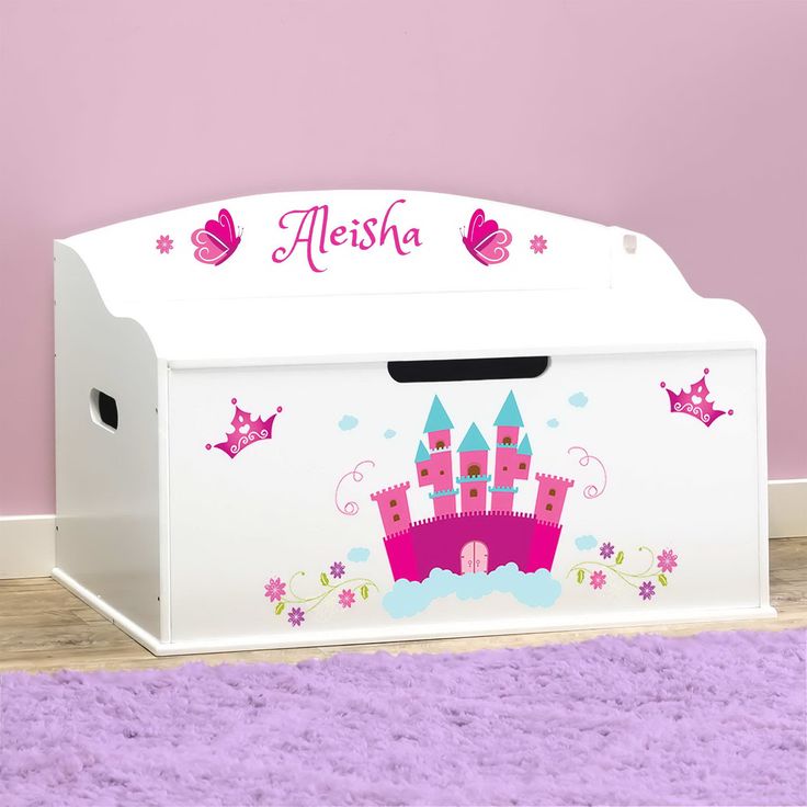 a white toy box with pink castle decals on the front and bottom, sitting on a purple rug