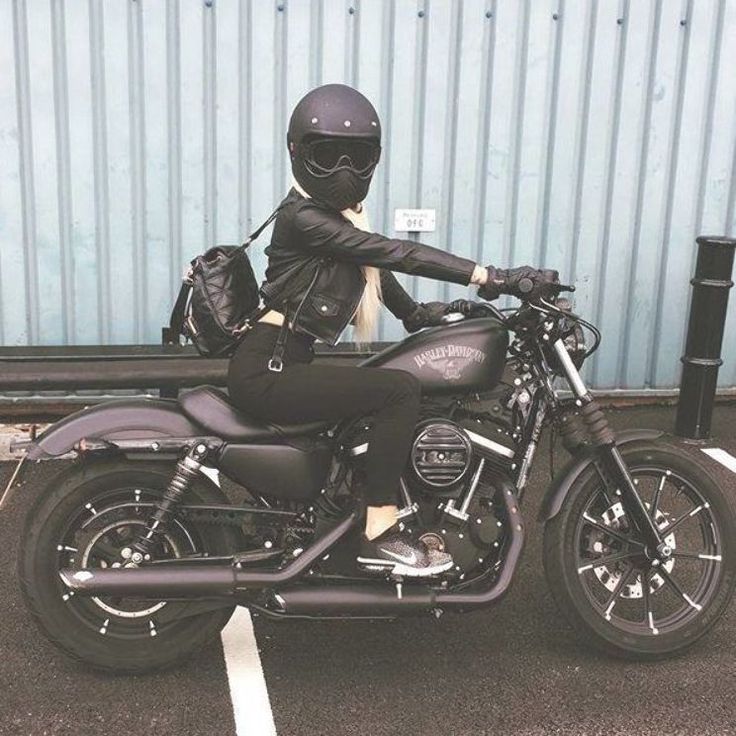 a woman sitting on top of a motorcycle in a parking lot next to a building