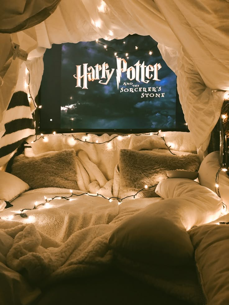 a harry potter poster on the wall above a bed with pillows and blankets covered in lights