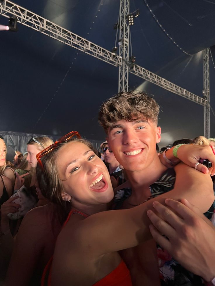 two people hugging each other in front of a crowd at a music festival or concert