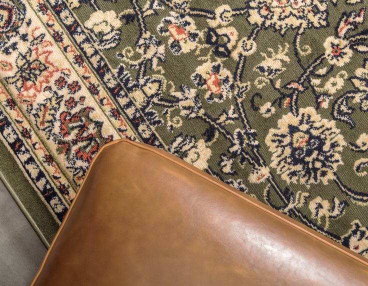 a brown leather chair sitting on top of a rug next to a green and white carpet