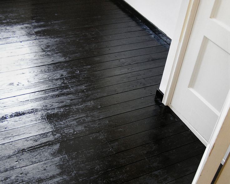 an open door on a wooden floor in front of a white wall and black floors