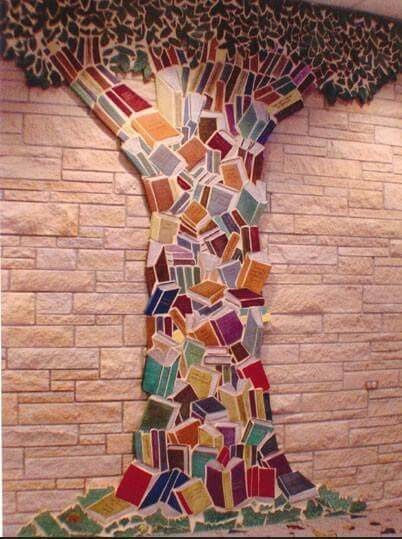 a mosaic art piece on the side of a brick wall with a tree made out of books