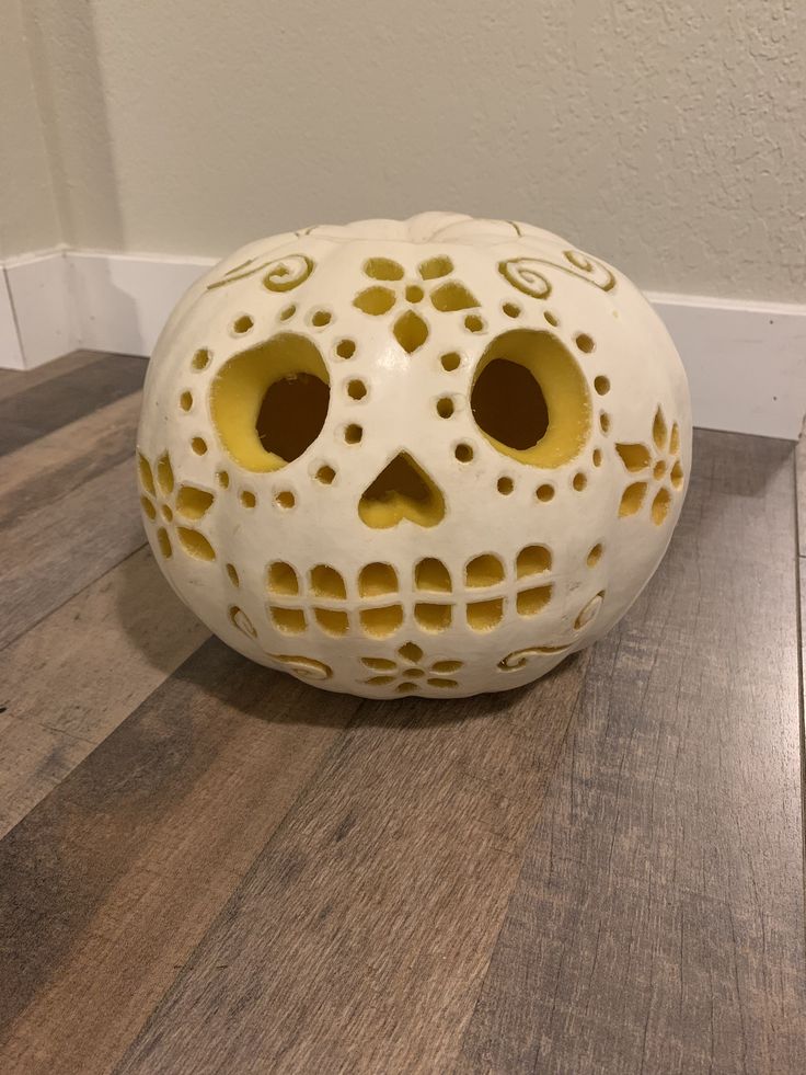 a white and yellow skull sitting on top of a hard wood floor next to a wall