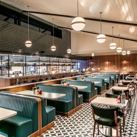 the interior of a restaurant with green and white booths