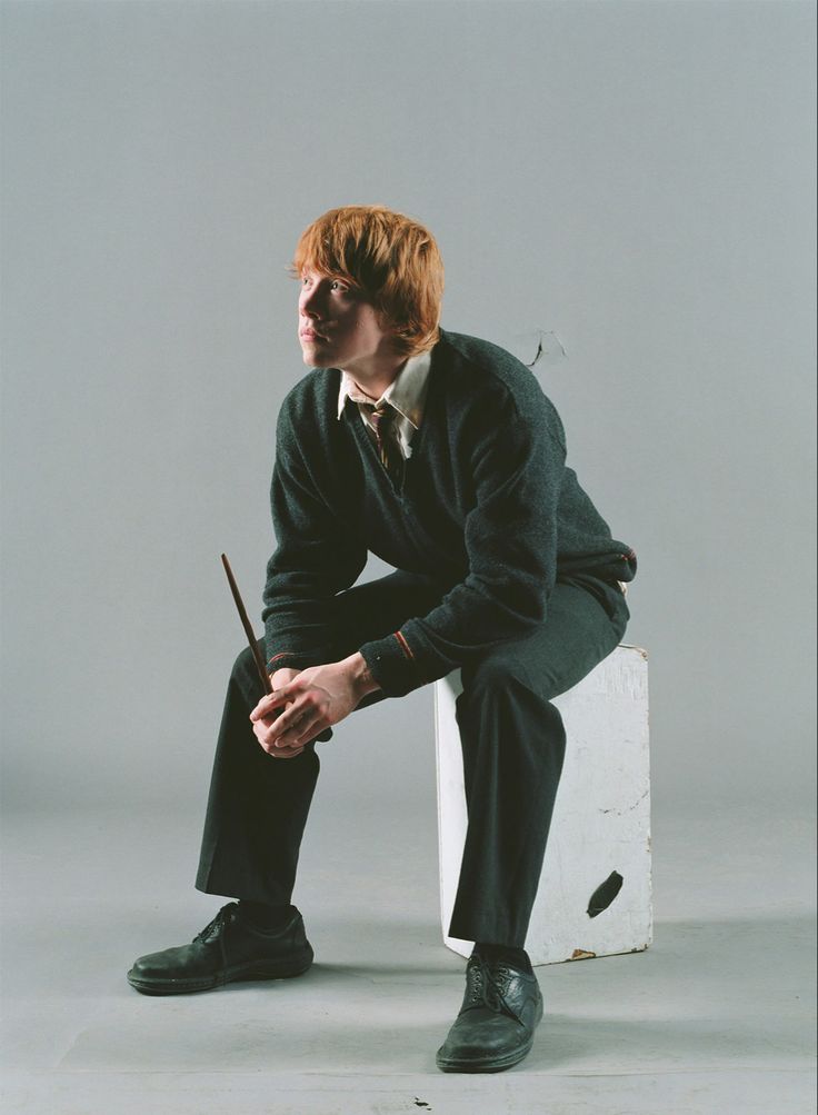 a man with red hair sitting on top of a white box holding a wand in his hand