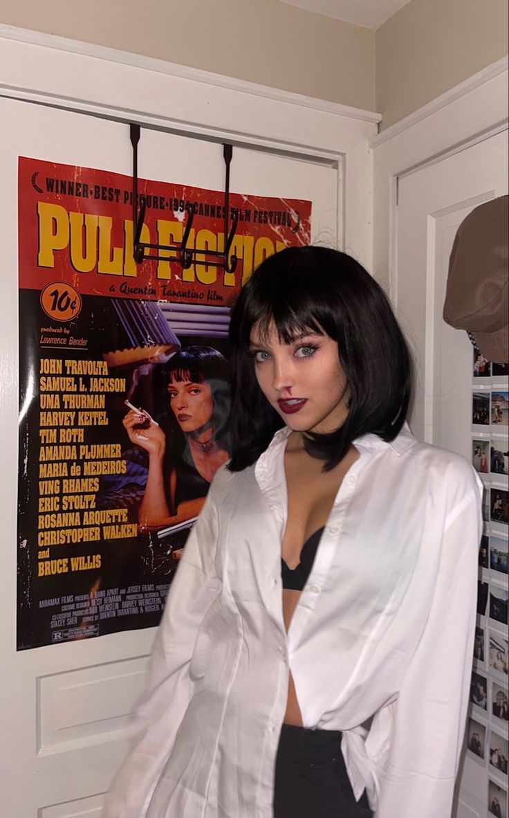 a woman standing in front of a movie poster wearing a white shirt and black skirt