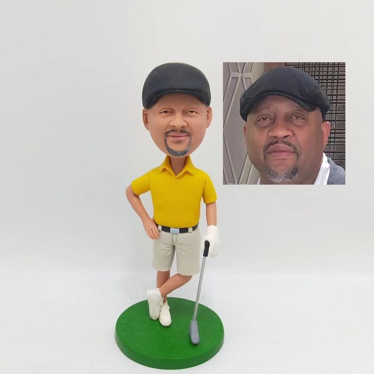 a bobble head golf player with a yellow shirt and black cap is posed in front of a white background