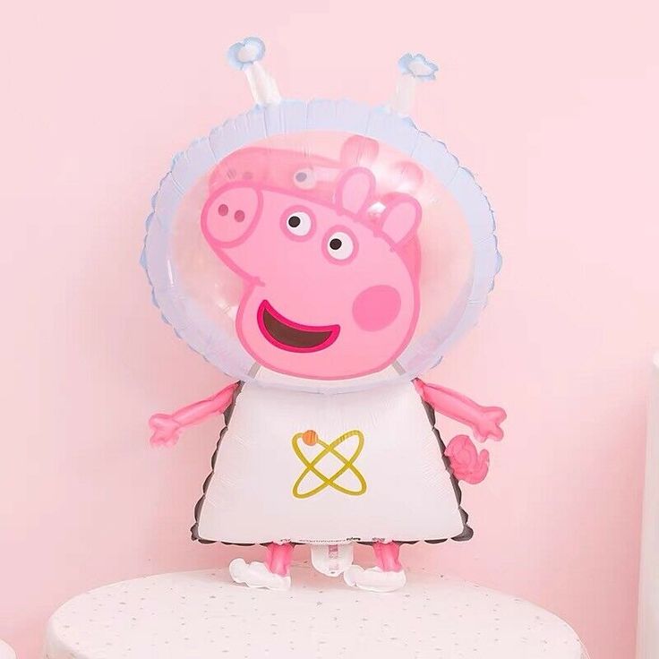 a peppa pig balloon sitting on top of a white table next to a pink wall