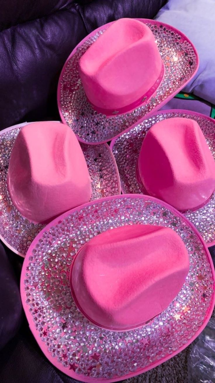 three pink hats sitting on top of each other in front of a purple couch with sequins