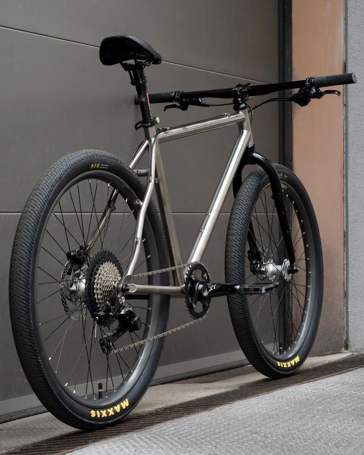 a bike parked in front of a garage door next to a bicycle wheel and chain