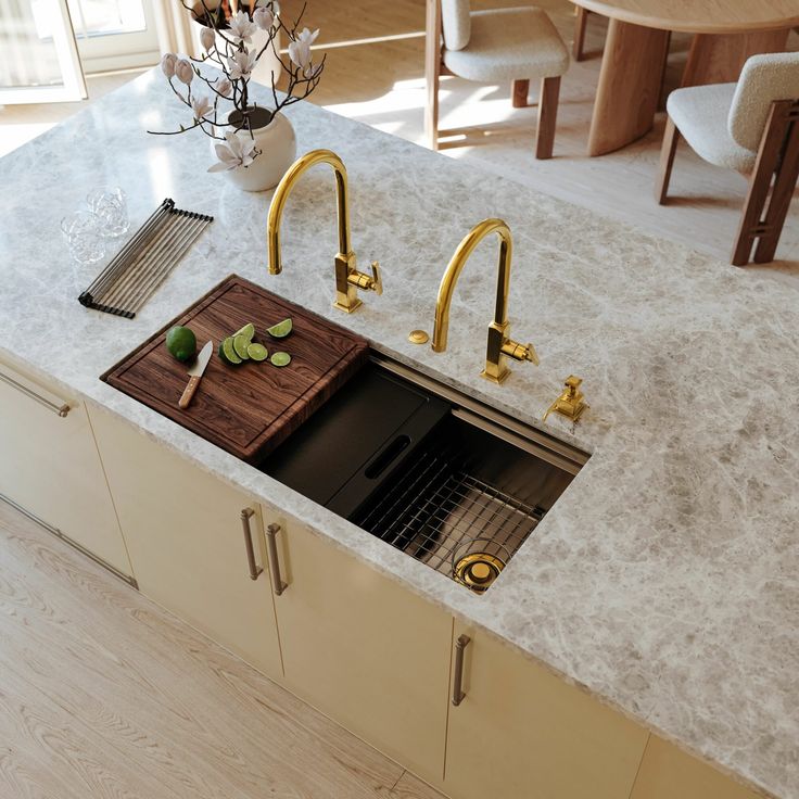 a kitchen sink with gold faucets and marble counter top next to an oven