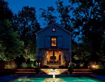 a house lit up at night with water running through the front yard and pool area