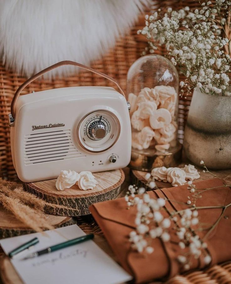 an old fashioned radio sitting on top of a wooden table next to flowers and books