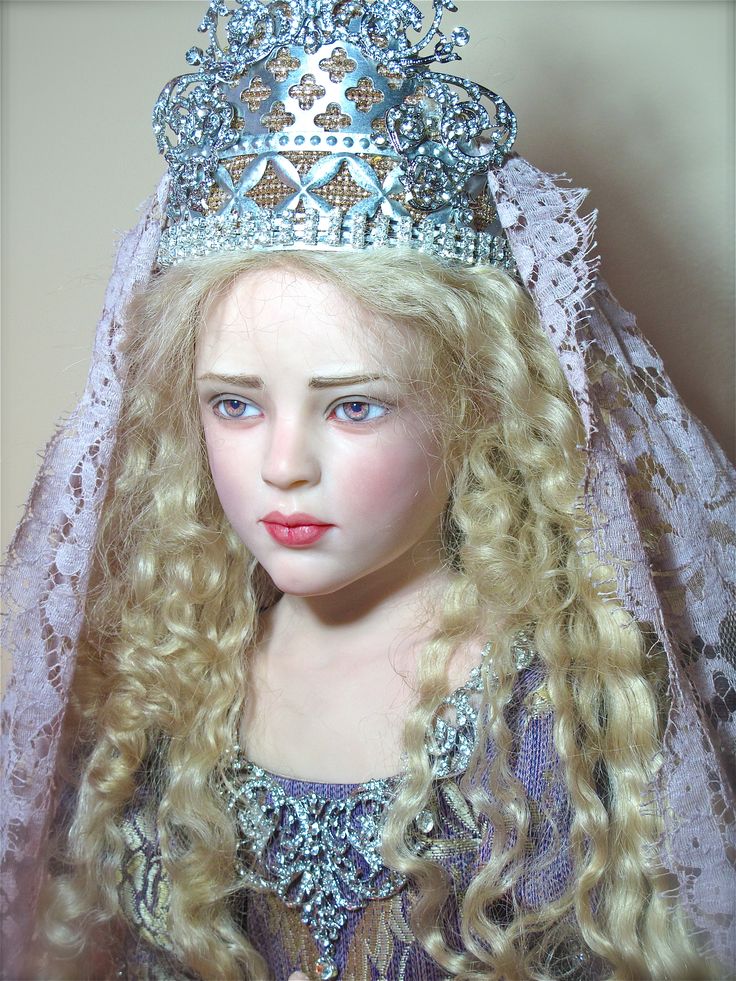 a close up of a doll wearing a tiara and dress with long blonde hair