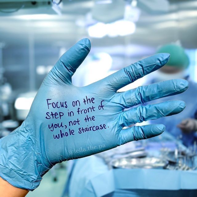 a person wearing blue gloves and writing on their hand in a hospital room with other medical equipment