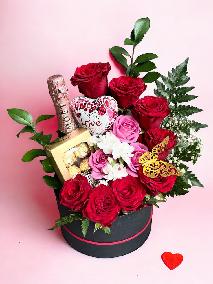 valentine's day flowers and chocolates in a heart shaped box on a pink background