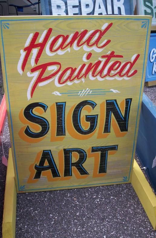 a sign that says hand painted in front of some other signs