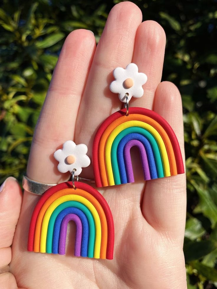 a pair of rainbow earrings with white flowers on each side and a flower in the middle