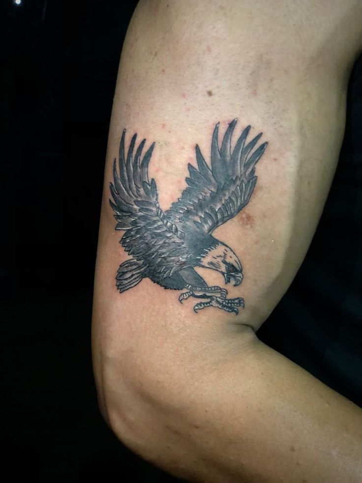 an eagle tattoo on the arm of a man's left arm, with black ink