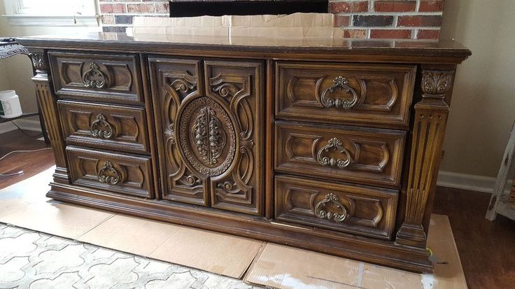 a large wooden dresser sitting on top of a hard wood floor next to a brick wall