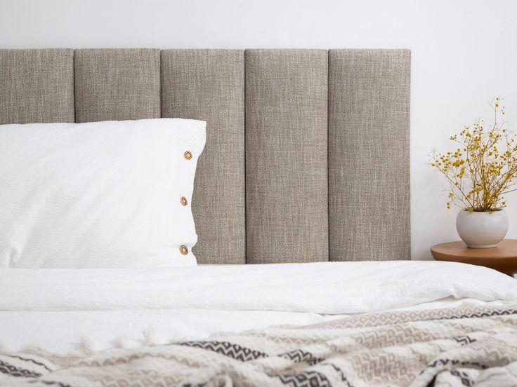 a bed with white sheets and pillows on top of it next to a wooden night stand