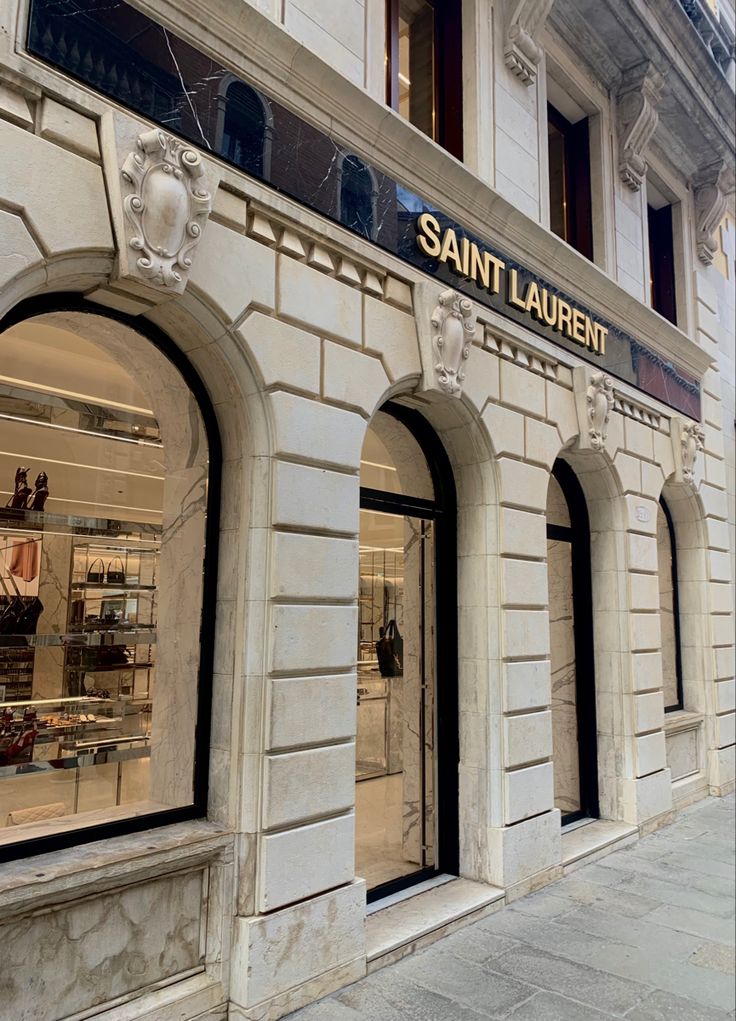 the storefront of saint laurent is decorated in white marble and features an ornate window display