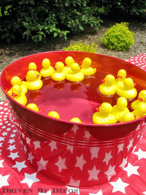 a red tub filled with yellow rubber ducks on top of a table covered in stars