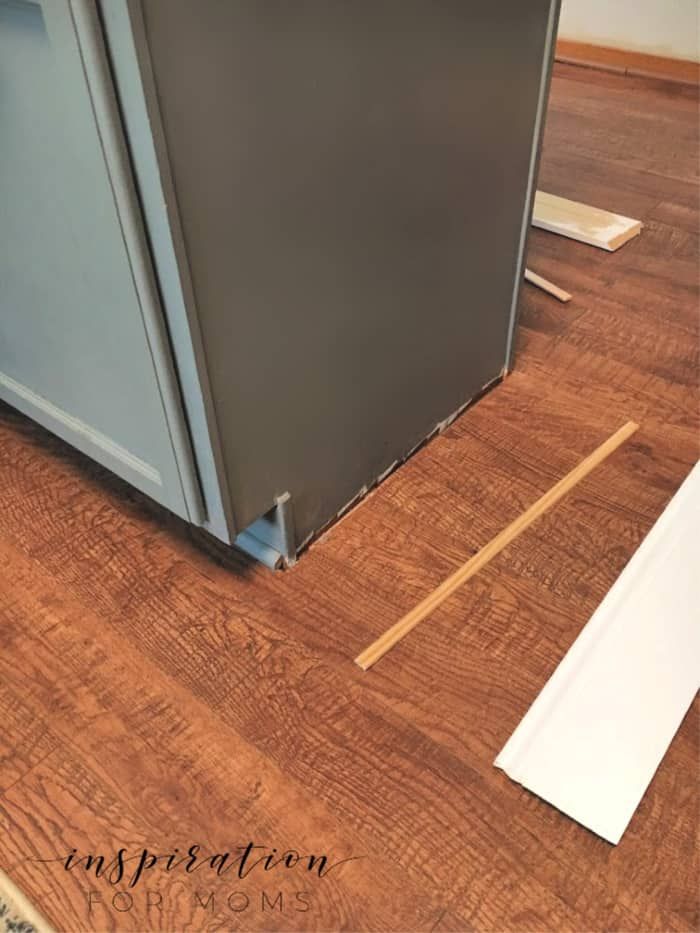 a small refrigerator sitting on top of a wooden floor next to a white piece of paper