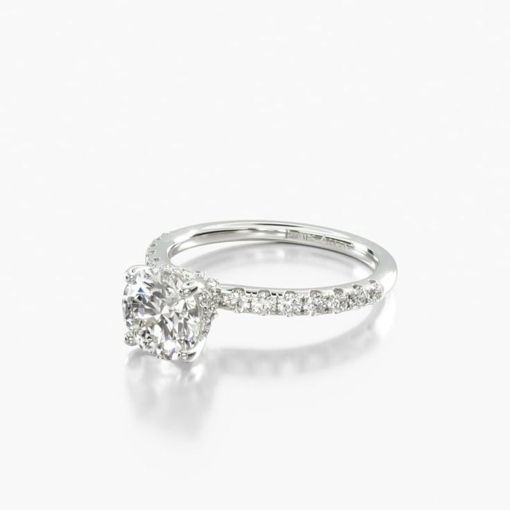 an engagement ring with a diamond on the top and side stones in the middle, against a white background