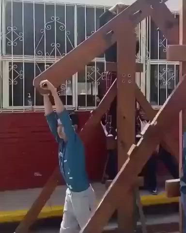 This may contain: a man standing in front of a wooden structure with his hands up to the ceiling